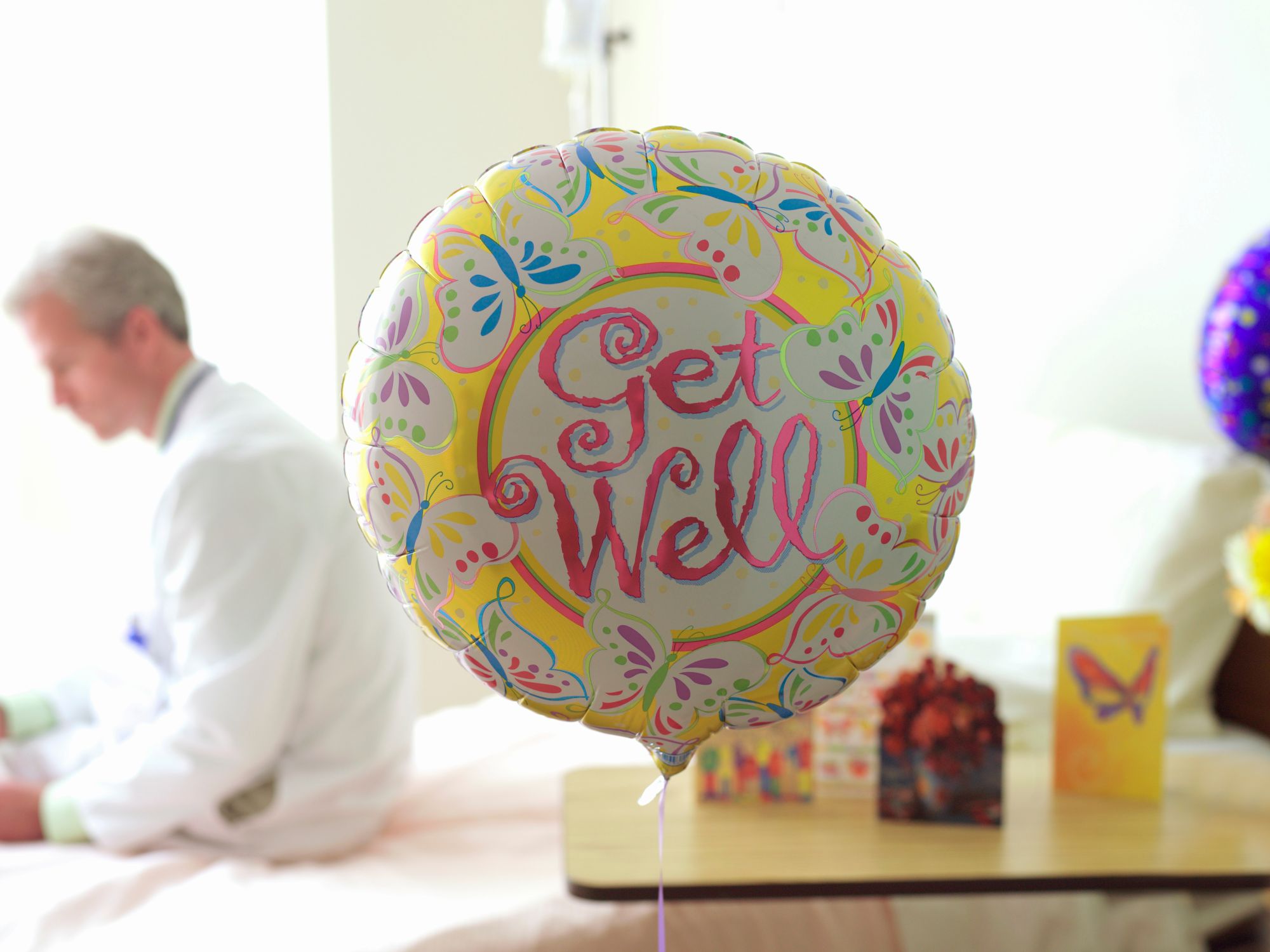 Digital get well soon card on a phone beside a cup of tea, flowers and a cosy blanket