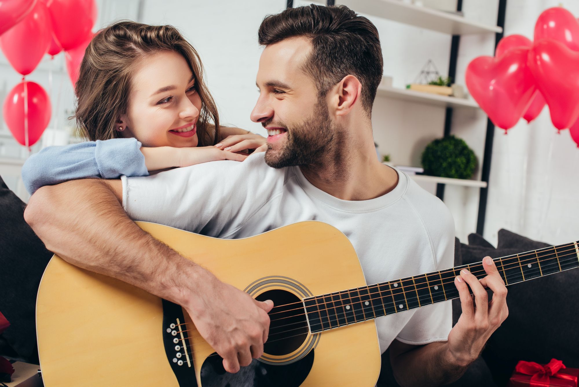 Couple listening to a custom love song through shared headphones on a sunlit afternoon